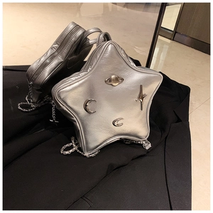 Detail of silver star-shaped crossbody bag featuring planetary and moon metal charms