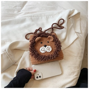 Gros plan détaillé d'un sac bandoulière lion au crochet à côté d'un téléphone portable