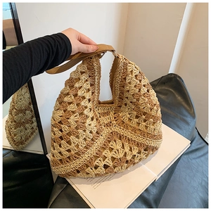 Detail of hollow-out straw handbag featuring contrast weave and brown leather handle
