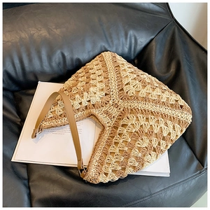 Detail of hand-woven straw tote with hollow diamond patterns and brown leather straps