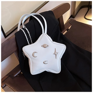 Close-up of white star-shaped bag with silver celestial charms on black blazer