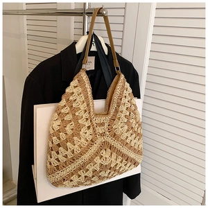 Close-up of two-tone beige and brown woven straw tote bag with leather straps