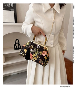 Détail d'un sac à main vintage en satin fleuri avec poignée en bambou et chaîne dorée