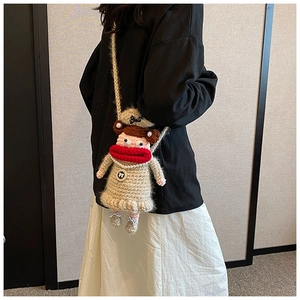 Détail du sac bandoulière fait main au crochet avec forme de poupée et collier de perles