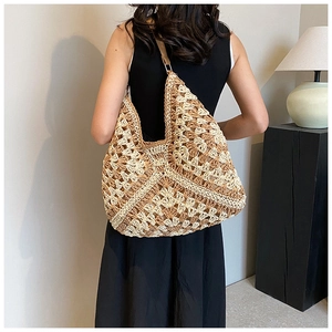 Detailed close-up of large woven straw bag with contrast crochet texture on a model