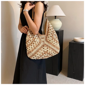 Hobo straw bag with brown leather shoulder strap shown on model in black dress
