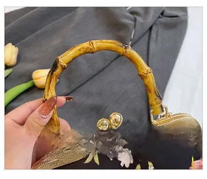 Detail of vintage floral shell bag featuring bamboo handle and golden metal clasp