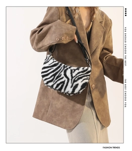 Detail of zebra print plush shoulder bag with black strap on a brown blazer outfit