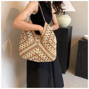 Detail of hand-woven straw bucket bag with hollow geometric patterns and leather strap