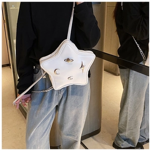 White star-shaped crossbody bag with metallic planet and moon charms on model