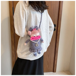 Détail d'un sac au crochet violet avec des lèvres roses et un collier de perles