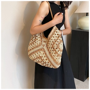 Detail of hand-woven straw tote bag with brown geometric crochet patterns on cream base