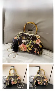 Detail of vintage floral silk handbag featuring a natural bamboo handle and silk tassel