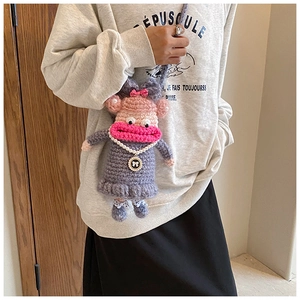 Détail d'un sac à bandoulière en crochet fait main avec collier de perles et nœuds roses