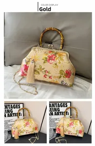 Detailed shot of vintage shell bag with bamboo handle, floral patterns and side tassel