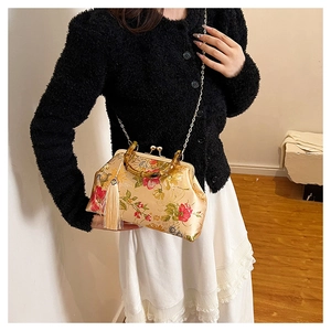 Detail of bamboo handle and floral satin shell bag with tassel and gold chain strap