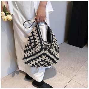 Detail of large crochet tote bag with black and white geometric pattern and leather handles