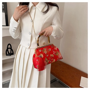 Close-up of red silk embroidery evening bag with bamboo handle and gold chain strap