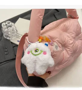 Detailed view of a pink quilted puffer handbag with a white plush monster charm