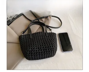 Close-up of black woven bucket bag showing detailed texture and smartphone size comparison