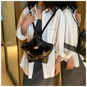 Star-shaped black crossbody bag with gold celestial metal charms shown on a model