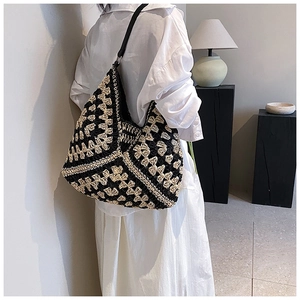Detail of woven geometric pattern and black leather strap on a large shoulder bag