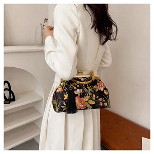 Détail du sac de soirée en satin fleuri avec poignée en bambou et bandoulière dorée