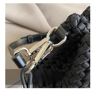Detailed macro view of silver metal hook hardware on a black woven leather bucket bag