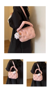 Detailed view of pink quilted puffer bag with plush doll charm and adjustable strap
