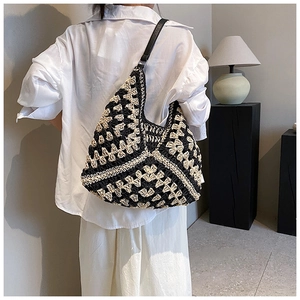 Macro detail of hand-woven geometric pattern hobo bag with contrast leather strap