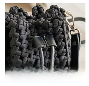 Macro detail of black woven bucket bag showing drawstring closure and satin texture