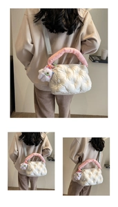 Close-up of a white quilted puffer bag with a plush monster charm and pink handles