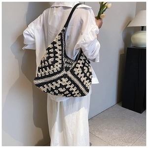 Detail view of woven crochet hobo bag with contrast geometric pattern on model