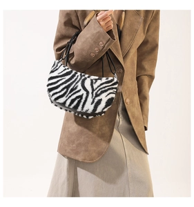Detail of zebra print plush crescent bag featuring smooth faux fur texture and black straps