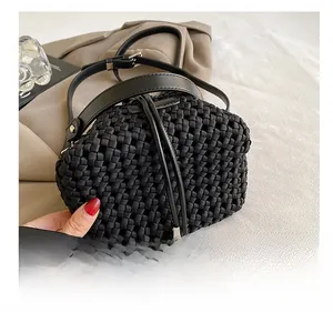 Close-up of black woven bucket bag showing intricate fiber texture and leather handle