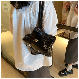 Close-up of black star-shaped crossbody bag with metallic cosmic decorations and thin strap