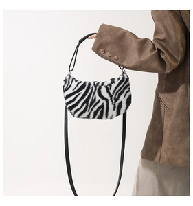 Detail of plush zebra print shoulder bag with black leather handle and crescent shape