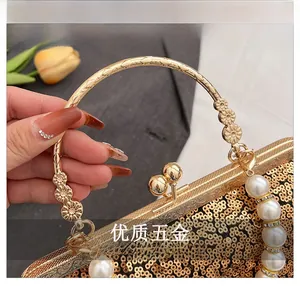 Detail of champagne gold sequined evening bag with white faux pearl chain and metal handle