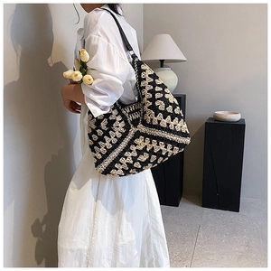 Detail view of woven shoulder bag featuring black and beige geometric diamond patterns