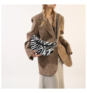 Detailed view of zebra print plush crescent bag with adjustable black strap on model