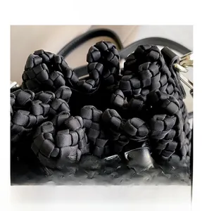 Detail of black woven bucket bag showing thick honeycomb texture and drawstring closure