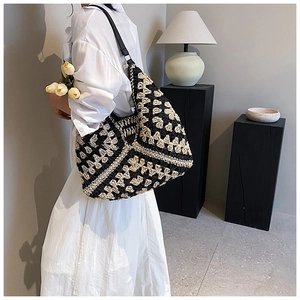 Detail of hand-woven geometric straw bag featuring contrast black and beige hollow patterns