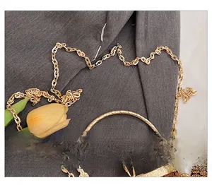 Detail of gold sequin evening bag with embossed metal handle and pearl accents