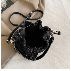 Detail of hand-woven black bucket bag with glossy texture and silver metal fasteners