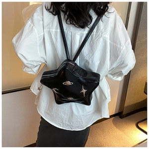 Detail of star-shaped black PU leather backpack with metallic celestial charms on person