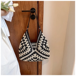 Detail of hand-woven crochet shoulder bag with geometric patterns hanging on a door