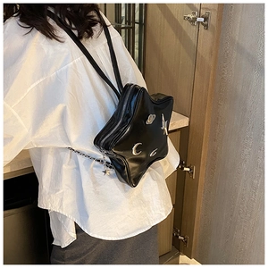 Detail of star-shaped black PU backpack with silver celestial metal charms worn by model