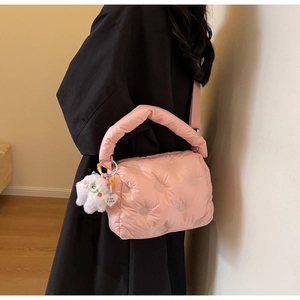 Detail of pink quilted down bag with plush charm and heart tag in cozy interior