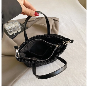 Close-up of black woven bucket bag with metal zipper and organized interior pockets