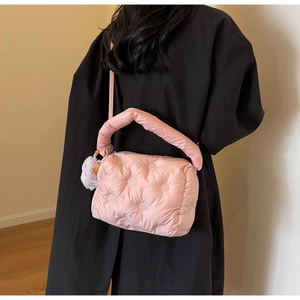 Detail of pink quilted down bag with polka dot stitching and heart-shaped pendant